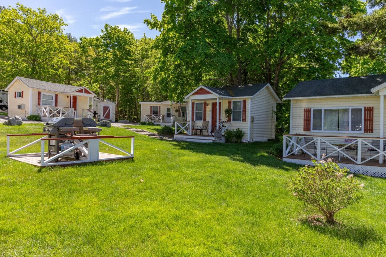 Une rangée de maisons mobiles avec une cour gazonnée et un barbecue.