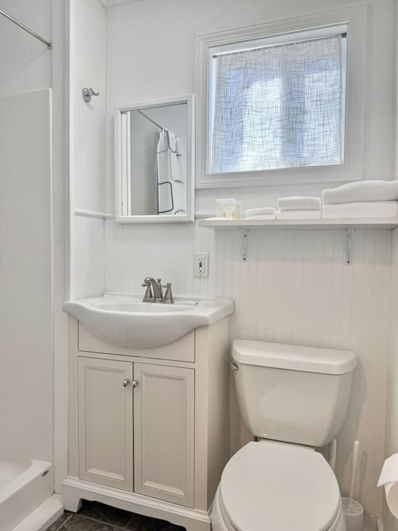 Une salle de bain avec un lavabo blanc, un miroir et des toilettes.