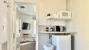 Cocina compacta con microondas, cafetera y un cubo de basura.