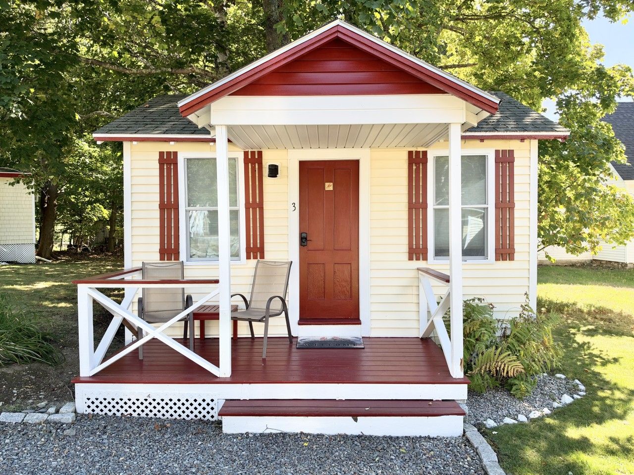 Ein kleines Haus mit Veranda, einer Tür und zwei Fenstern.