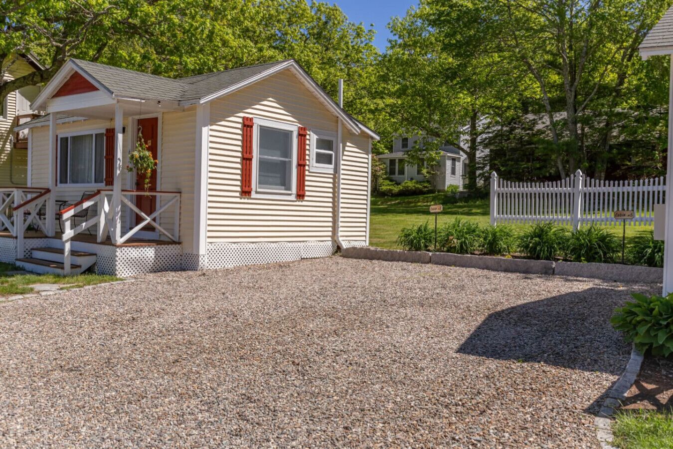 A small, single-story house with a porch and a gravel driveway.