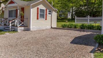 A small, single-story house with a porch and a gravel driveway.