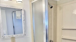 A bathroom with a white sink, mirror, and shower enclosure.