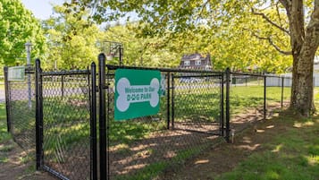 A fenced dog park with a sign welcoming visitors.