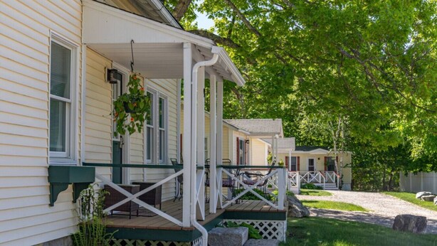 A row of mobile homes with individual porches, each featuring a small table and chairs.