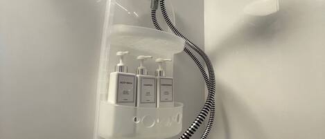 A shower with a handheld showerhead and a soap dispenser mounted on the wall.