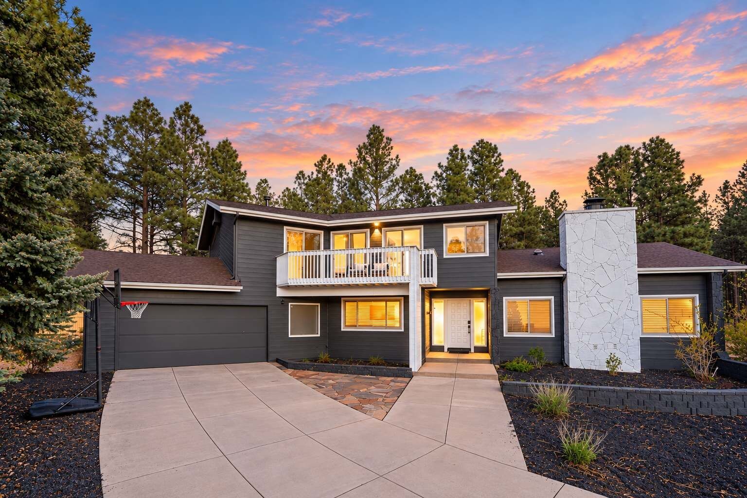 A two-story house with a balcony, a garage, and a driveway.