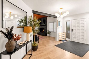 A modern living room with a fireplace, a large mirror, and a console table with decorative items. - Family-Friendly • Hot Tub • Fire Pit • EV Charger (Flagstaff)