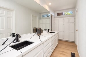 A modern bathroom with a long vanity, a large mirror, and a window above the cabinets. - Family-Friendly • Hot Tub • Fire Pit • EV Charger (Flagstaff)