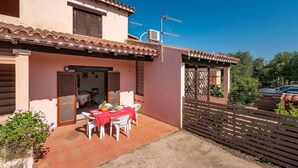 A two-story house with a patio area featuring a table set for dining. - San Teodoro Flat Steps From the Beach (San Teodoro)