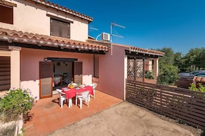 A two-story house with a patio area featuring a table set for dining. - San Teodoro Flat Steps From the Beach (San Teodoro)