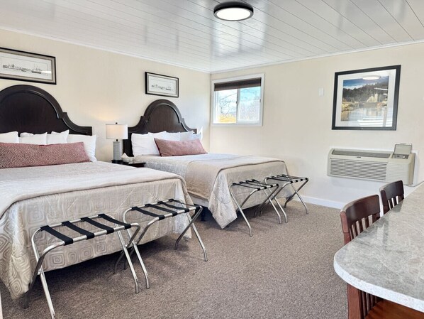 Hotellihuone, jossa on kaksi sänkyä, pöytä, tuolit ja ikkuna.