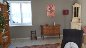 A living room with a wooden cabinet, a chair, a small table, and a window. - In the quiet countryside, single-storey house (Mouilleron-le-Captif)
