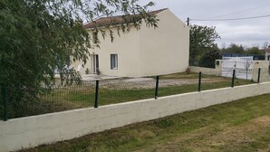 A white building with a tiled roof, surrounded by a white wall and a metal fence. - In the quiet countryside, single-storey house (Mouilleron-le-Captif)