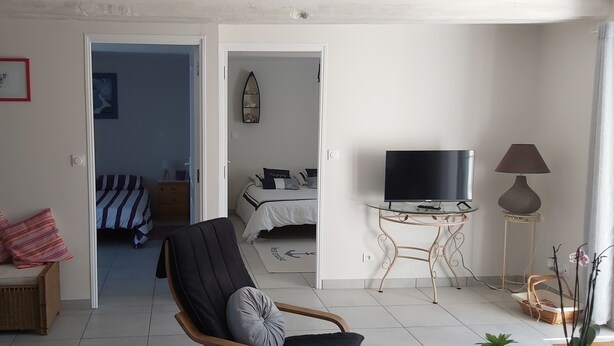 A living room with a TV, a chair, a lamp, and a bed in the background. - In the quiet countryside, single-storey house (Mouilleron-le-Captif)