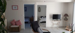 A living room with a TV, a chair, a lamp, and a bed in the background. - In the quiet countryside, single-storey house (Mouilleron-le-Captif)