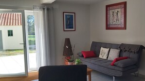 A living room with a grey sofa, red and white cushions, a potted plant, and two framed artworks on the wall. - In the quiet countryside, single-storey house (Mouilleron-le-Captif)