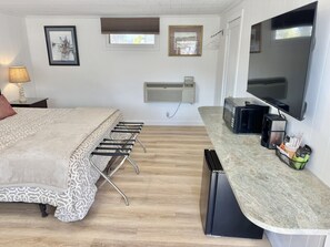 A bedroom with a bed, a desk, a TV, and a window. - Gallagher`s Travels Room 12 (King Bed) (Bar Harbor)