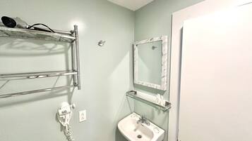 A bathroom with a white sink, a mirror with a marble frame, and a hairdryer on a metal shelf.