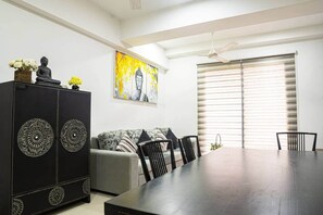 A dining area with a dark wooden table, black chairs, a grey sofa with patterned cushions, and a black cabinet with decorative panels. - H2o Residences Colombo (Colombo)