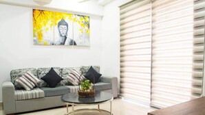 A living room with a grey sofa, black and white pillows, a round coffee table with a basket, and a large window with blinds. - H2o Residences Colombo (Colombo)