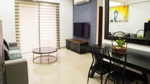 A modern living room with a round table, a sofa, a TV, and a large mirror. - H2o Residences Colombo (Colombo)