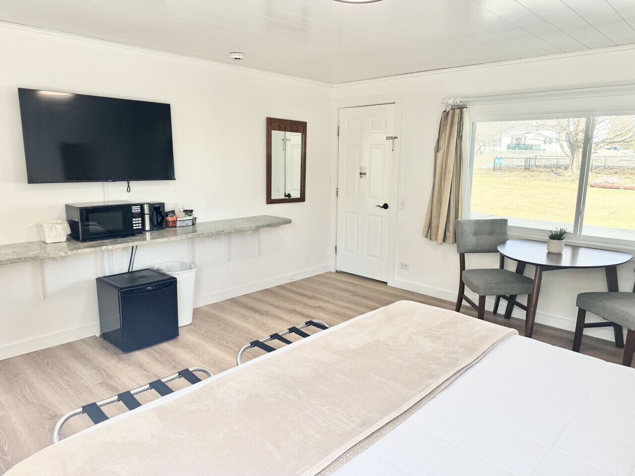 Habitación de hotel con cama, televisión, kitchenette pequeño, ventana con vistas y zona de estar.
