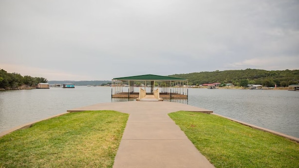 A lakeside dock with a gazebo, surrounded by grassy banks and a calm water body. - Water front cabin #12 Cabin in Graham, steps from Possum Kingdom Lake (Graham)