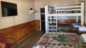 A room with a bunk bed, a single bed, a television mounted on the wall, and a ceiling fan. - Water front cabin #12 Cabin in Graham, steps from Possum Kingdom Lake (Graham)