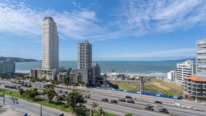 A coastal cityscape with high-rise buildings, a busy road, and a clear view of the sea. - Apartment Sea View 500 m From the Beach Roo0401 (Itapema)