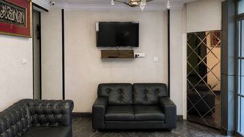 Una sala de estar moderna con un televisor de pantalla plana montado en la pared, un sofá de cuero negro y un sillón a juego.