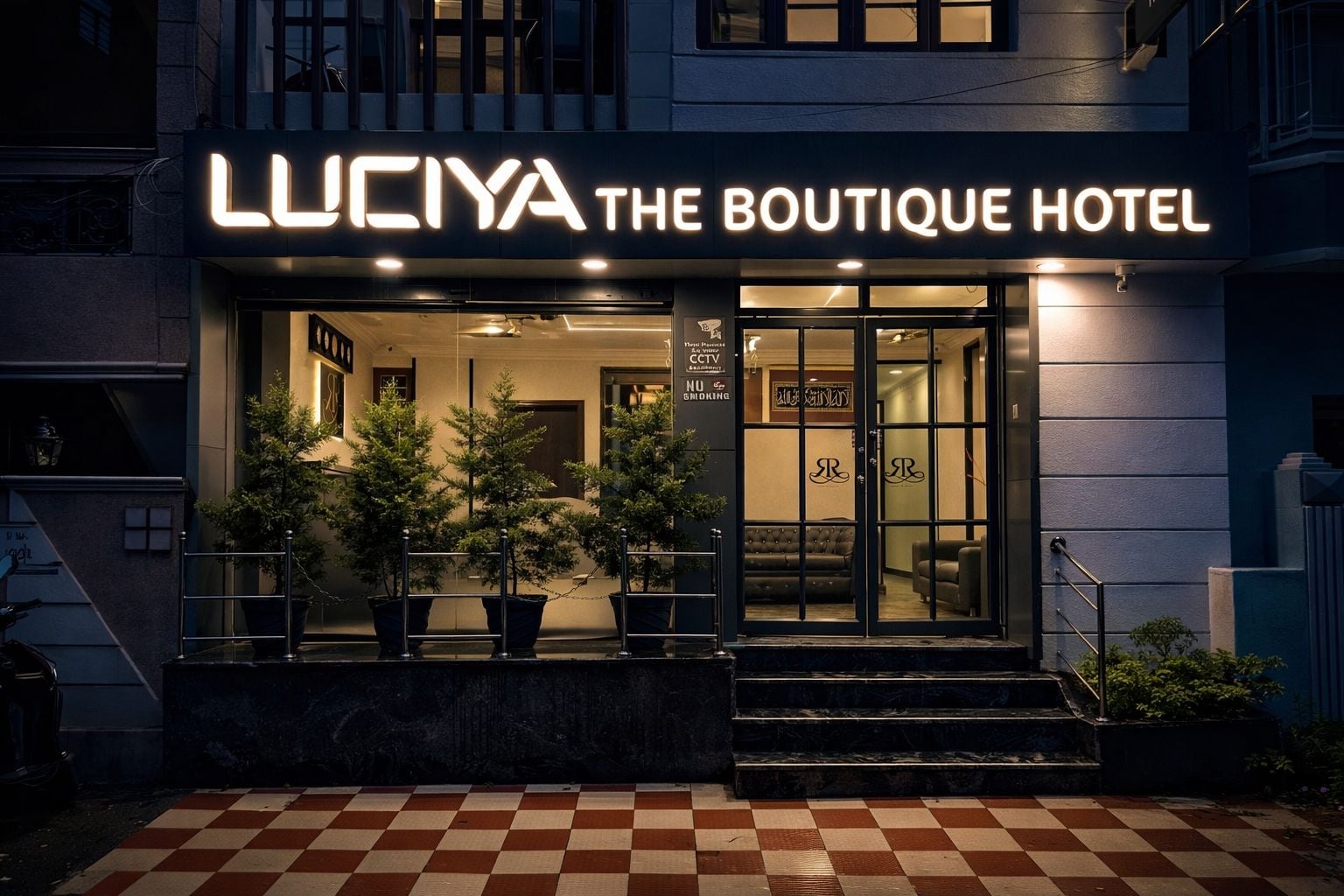 Der Eingang des Luciya The Boutique Hotel mit Schachbrettboden, Topfpflanzen und einem Schild mit Hinweis auf Videoüberwachung und Rauchverbot.