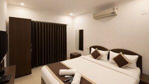 Quarto de hotel com cama, televisão, escrivaninha e guarda-roupa.