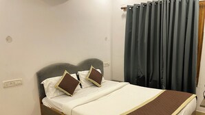 A neatly made bed with a brown quilted bedspread, two pillows with brown and white covers, and a dark grey headboard. - Luciya The Boutique Hotel (Bengaluru)