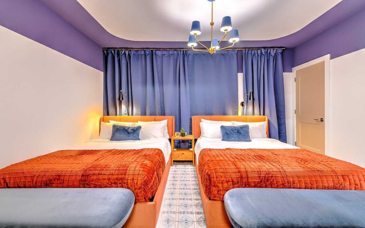 Ein Schlafzimmer mit zwei Betten, einer Chandelüster und einer Tür.