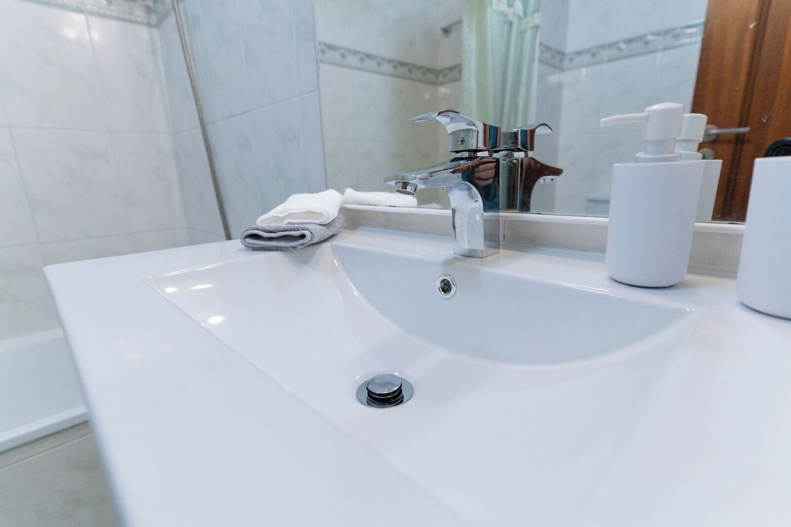 A modern bathroom with a white sink, a mirror, and a towel.
