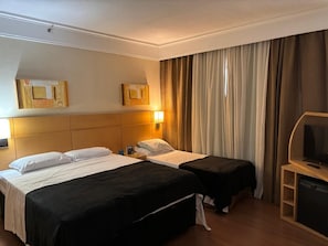 Ein Hotelzimmer mit zwei Betten, einem Fernseher und einem Schreibtisch.