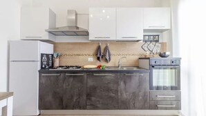 A modern kitchen with a built-in stove, a refrigerator, and a double oven. - Cozy Flat Steps From Porto Torres Beaches (Porto Torres)