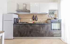A modern kitchen with a built-in stove, a refrigerator, and a double oven. - Cozy Flat Steps From Porto Torres Beaches (Porto Torres)