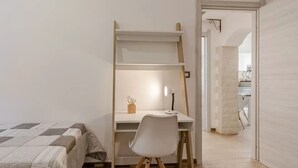 A bedroom with a bed, a desk with a chair, and a ladder. - Cozy Flat Steps From Porto Torres Beaches (Porto Torres)