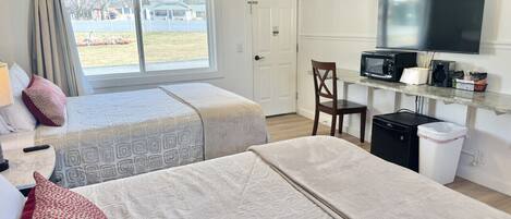 Une chambre d’hôtel avec deux lits, une télévision, un four à micro-ondes, une petite table et une chaise.