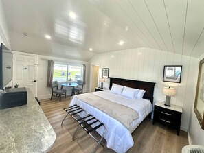 A bedroom with a bed, bedside tables, a desk, and a chair. - Gallagher`s Travels Room 5 (King Bed) (Bar Harbor)