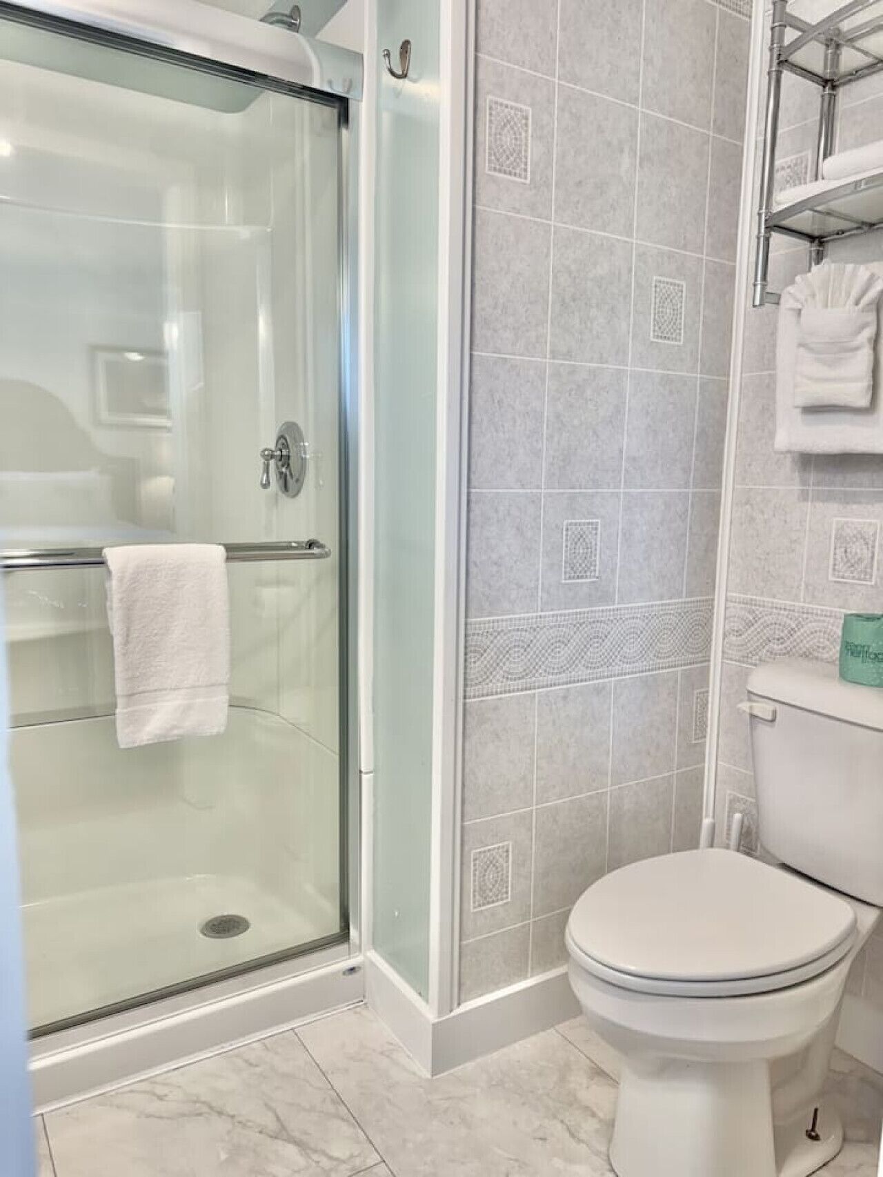 A bathroom with a glass-enclosed shower, a toilet, and a tiled wall.