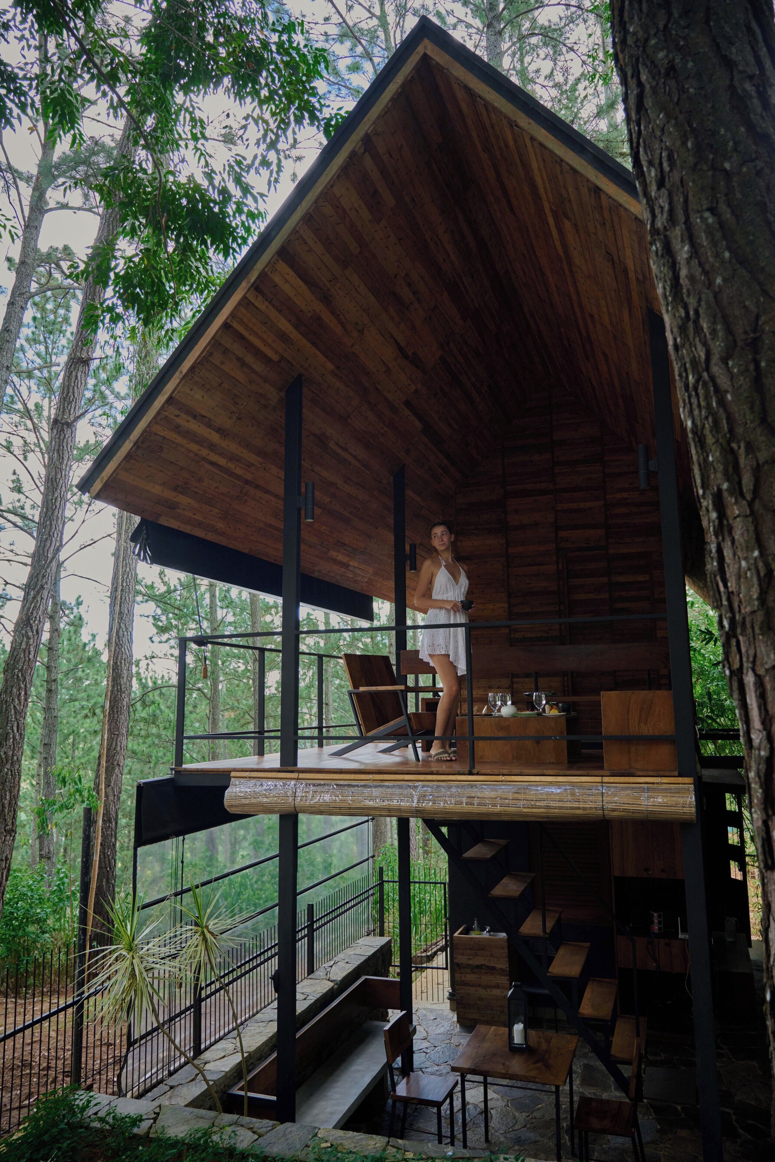 A wooden cabin with a balcony, surrounded by trees.