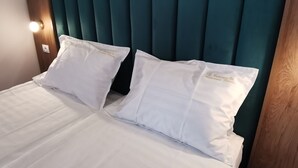 A bed with white linens and two pillows, a wooden headboard, and a wall-mounted light. - Pensiunea Rasnov (Rasnov)