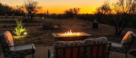 An outdoor seating area with a fire pit, two chairs, and a table.