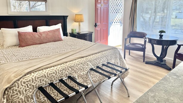 Une chambre d’hôtel avec un lit, un bureau, une chaise, une table et une porte.
