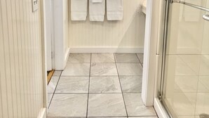 Une salle de bain avec une douche, une fenêtre et un sol carrelé.