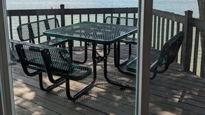 A wooden deck with picnic tables and chairs overlooking a lake. - Charming Stone Cottage On Lake James / Lone Tree Point (Angola)