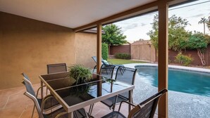 Eine Terrassenfläche mit Pool, Tisch und Stühlen sowie Blick auf den Garten.